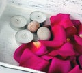 Stones, candles and pink rose petals on a white shabby chic tray. Spa welness concept Royalty Free Stock Photo