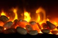 Stones in the fireplace, behind which fluttering flares of flame. Close-up.Black background Royalty Free Stock Photo