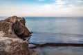 Stones flat in water and rocks on seashore, blurred water movement Royalty Free Stock Photo