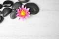 Stones with lotus flower and space for text on wooden background, flat lay. Zen lifestyle Royalty Free Stock Photo