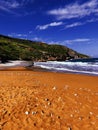 Stones on orange sand beach, waves in distance Royalty Free Stock Photo