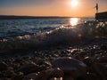 Stones and pebbles against waves and sunset. A silhouette of an angler