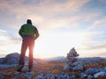 Stones pyramid on Alpine gravel mountain summit. Daybreak horizon above blue mist in valley.