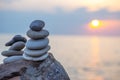 Stones pyramid on sand symbolizing zen, harmony, balance. Ocean at sunset in the background Royalty Free Stock Photo