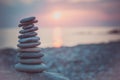 Stones pyramid on sand symbolizing zen, harmony, balance. Ocean at sunset in the background Royalty Free Stock Photo