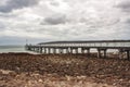 Stones scattered at the shore of Emu Bay with historic jetty during cast cloudy sky on Kangaroo Island in Australia. a Royalty Free Stock Photo