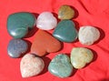 Stones in the shape of heart lie on a red background. Heart made of natural quartz stone, rhodochrosite, jade, aventurine and