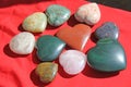 Stones in the shape of heart lie on a red background. Heart made of natural quartz stone, rhodochrosite, jade, aventurine and