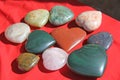 Stones in the shape of heart lie on a red background. Heart made of natural quartz stone, rhodochrosite, jade, aventurine and