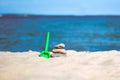 Pretty beach sand toys on dune with gentle waves with sailboat in distance under blue sky Royalty Free Stock Photo