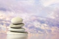 stones in a vertical pile in the water against the sky with clouds at sunset