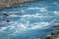 Stones in water riffle of mountain river. Powerful water stream among stones in mountain creek with rapids. Fast flow among rocks Royalty Free Stock Photo