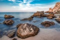 Stones in water and rocks on seashore, blurred water movement Royalty Free Stock Photo