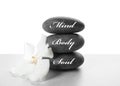 Stones with words MIND, BODY, SOUL and orchid flower on light background. Zen lifestyle