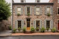 stonewalled house with tall, shuttered windows by a cobblestone street