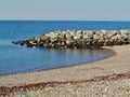 Stony bay with stone built wall with large blocks of rock and sea in background