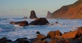 Stony beach at evening. The waves crash on rocky shore, pebbles, volcanic basalt in Tenerife Island. Sea water splashes Royalty Free Stock Photo