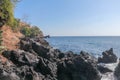 Stony coast with black lava rocks. Reef on the Balinese Sea. An erupting stiff lava in the ocean. Huge pieces of volcanic rock. Royalty Free Stock Photo