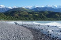 Stony Mangamaunu, beach near Kaikoura with surf rolling in and surfers with mountain and snow backdrop