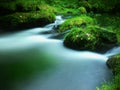 Stony weir on small mountain river. Stream is flowing over square blocks and makes milky water.