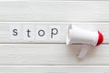 Stop announcement symbol with megaphone and text on white wooden background top view