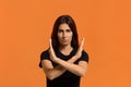 Stop, calm down. Serious caucasian woman in black t-shirt crosses hands over chest, looks with censure, expresses a negative