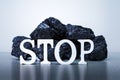 Word STOP with Coal Stack on grey background. Royalty Free Stock Photo