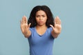 Stop concept. Serious black lady making stop hand gesture on blue studio background, selective focus Royalty Free Stock Photo