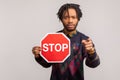 Hey you, stop. Concerned worried african guy with dreadlocks holding stop sign and pointing finger at camera with serious anxious Royalty Free Stock Photo