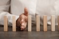 Stop the domino effect concept, the hand blocks the fall of a row of wooden blocks, risk insurance Royalty Free Stock Photo