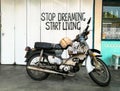 Stop dreaming start living quote slogan on background with old motorbike on foreground