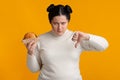 Overweight girl holding hamburger and showing thumb down, despise fast food Royalty Free Stock Photo