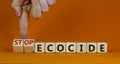 Stop ecocide symbol. Businessman turns wooden cubes and changes words ecocide to stop ecocide. Beautiful orange background, copy