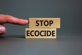 Stop ecocide symbol. Wooden blocks with words stop ecocide. Businessman hand. Beautiful grey background, copy space. Business,