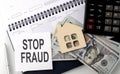 STOP FRAUD - the inscription of text on the sticker on planning with dollars and calculator