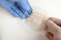 STOP GMO from wooden letters. One hand in a white medical and the other in a blue lab glove together hold a petri dish. Concept of Royalty Free Stock Photo