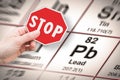 Stop heavy metals - Concept image with hand holding a stop sign against a Lead chemical element with the Mendeleev periodic table Royalty Free Stock Photo