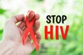 Stop HIV text for immunodeficiency virus disease red ribbon symbol on man hand