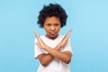 Stop, I`m warning. Portrait of angry determined little boy with curls crossing hands and looking at camera with aggression