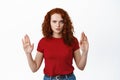 Stop I said no. Serious and confident redhead girl showing block taboo gesture, raising hands to prohibit or reject