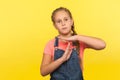 Stop, limit gesture. Portrait of tired unhappy little girl with braid in denim overalls showing timeout, child asking break