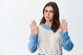 Stop now. Serious frowning woman raising hands with block gesture, saying no and refusing bad offer, standing in sweater