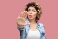 Stop. Portrait of angry young woman with curly hairstyle in casual blue shirt standing with stop hand gesture and blocking,