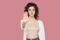 Stop. Portrait of serious beautiful brunette young woman with curly hairstyle in casual style standing with stop hands gesture and