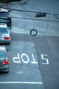 Stop sign area with parked cars and hanging traffic light wires with white painted words in afternoon shade in the city downtown