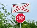 A STOP sign in front of a railway crossing. Red against a background of green trees, close-up. Royalty Free Stock Photo