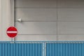 Stop sign next to a blue fence in front of a stone light-colored wall Royalty Free Stock Photo