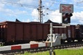 Stop sign and red lights on railway crossing with passing cargo train