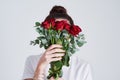 Stop and smell the roses. Studio shot of an unrecognizable woman covering her face with flowers against a grey Royalty Free Stock Photo