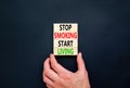 Stop smoking start living symbol. Concept words Stop smoking start living on cubes. Beautiful black background. Doctor hand.